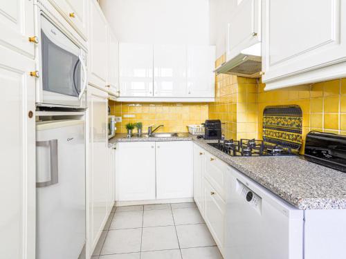 cocina con armarios blancos y azulejos amarillos en Apartment La Floride Promenade des Anglais by Interhome, en Niza