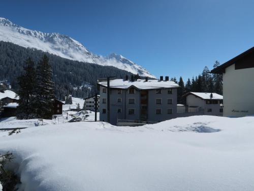 a building in the snow in front of a mountain at Apartment Chesa Boffalora by Interhome in Valbella