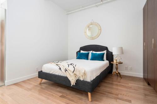 a bedroom with a bed with blue pillows and a mirror at Le Merrill - Vieux Montréal in Montréal