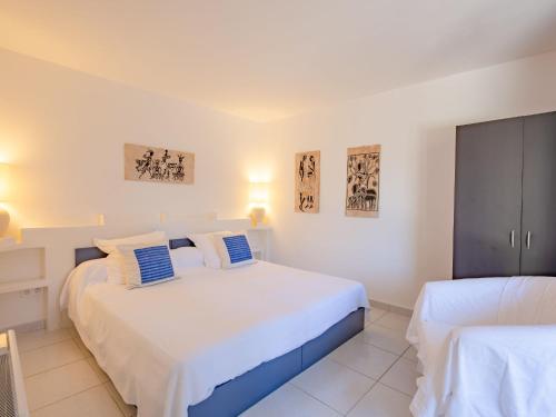 um quarto com 2 camas com lençóis brancos e almofadas azuis em Apartment Les Collines de valescure by Interhome em Saint-Raphaël