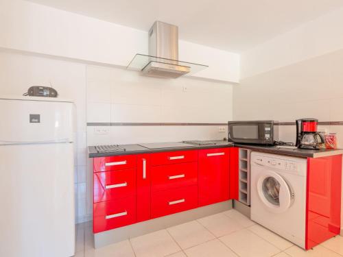 - une cuisine avec des placards rouges et un lave-linge dans l'établissement Apartment Les Collines de valescure by Interhome, à Saint-Raphaël