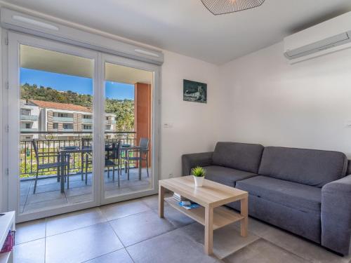 a living room with a couch and a table at Apartment Le Jardin du Loderi-2 by Interhome in Bormes-les-Mimosas