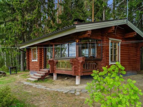 ein kleines Blockhaus mit einer Veranda im Wald in der Unterkunft Holiday Home Huvilakoti 2 by Interhome in Puromäki