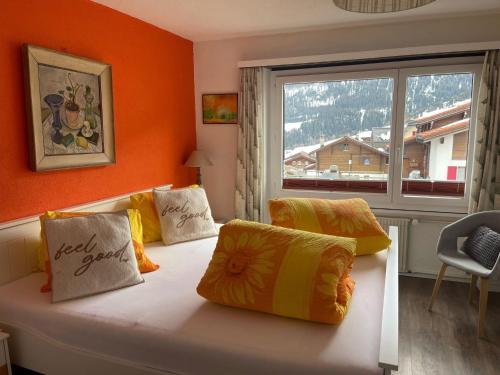 Zimmer mit einem Bett mit orangefarbenen Wänden und einem Fenster in der Unterkunft Apartment Tgesa Pitgmun by Interhome in Sedrun