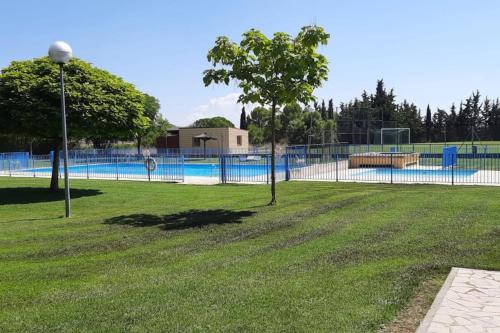 uma cerca em torno de uma piscina com uma árvore num parque em 5 bedrooms house with wifi at Alera em Sádaba