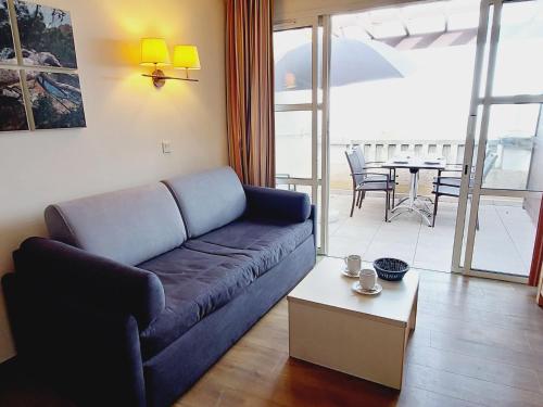 ein Wohnzimmer mit einem blauen Sofa und einem Tisch in der Unterkunft Apartment Village Cap Estérel - Le Village-67 by Interhome in Agay - Saint Raphael