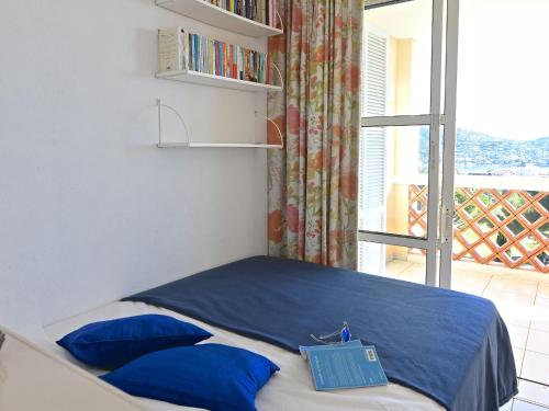 une chambre avec un lit avec des oreillers bleus et une fenêtre dans l'établissement Apartment Les Bastides - O5 018 by Interhome, à Agay
