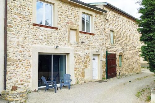 une maison en pierre avec deux chaises bleues devant elle dans l'établissement Gîte de la Plaine, à Chanas