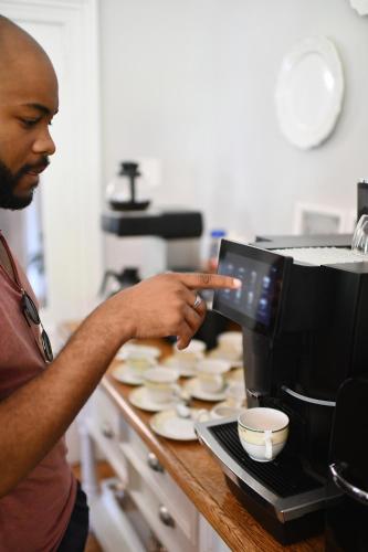 a man standing in a kitchen using a coffee maker at Bonne Esperance Boutique Guest House in Stellenbosch