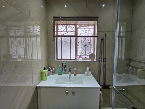 a bathroom with a sink and a shower and a window at Downham Views in Johannesburg