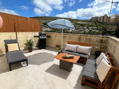 een patio met een tafel en stoelen en een parasol bij Arzella - spacious two bedroom apartments in Xlendi