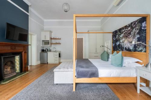 a bedroom with a canopy bed and a fireplace at Bonne Esperance Boutique Guest House in Stellenbosch