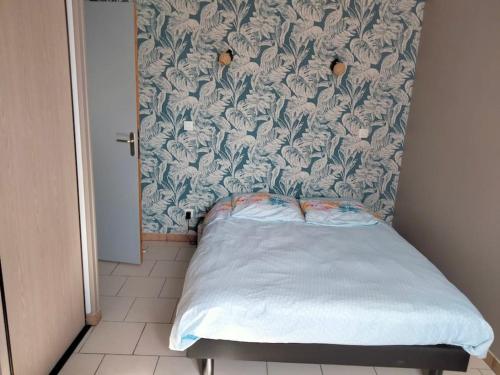 ein kleines Bett in einem Schlafzimmer mit Blumentapete in der Unterkunft Ferme de l'Etang - Gîte in Épuisay