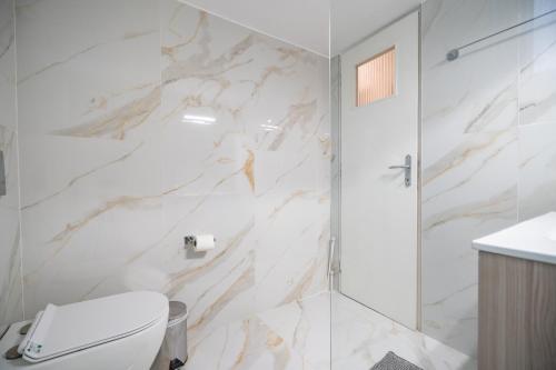 a white bathroom with a shower and a toilet at Neo Irakleio train st. 1 bedrm 4 pers. apartment in Athens