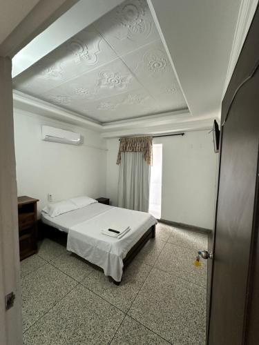 ein Schlafzimmer mit einem weißen Bett und einem Fenster in der Unterkunft Apartaestudio Luiggis Cucuta in Cúcuta
