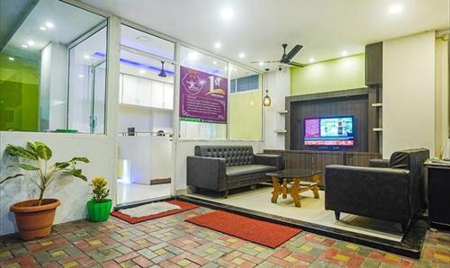 a living room with couches and a flat screen tv at The JK Hotel - Opp Railway Station, Civil Lines, Sadar, Nagpur in Nagpur
