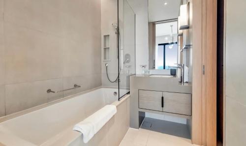 a white bathroom with a tub and a sink at Address Beach Resort Apartment in Dubai