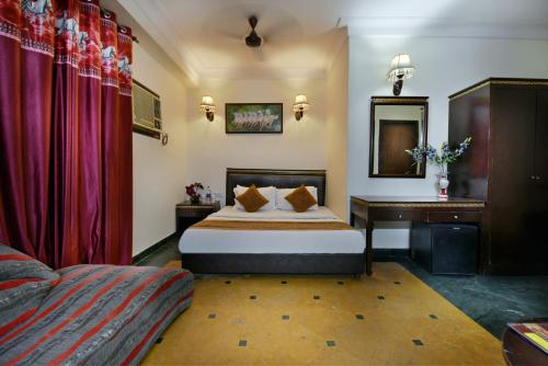 a hotel room with a bed and a desk at Hotel By Yellow Revels Plum in New Delhi