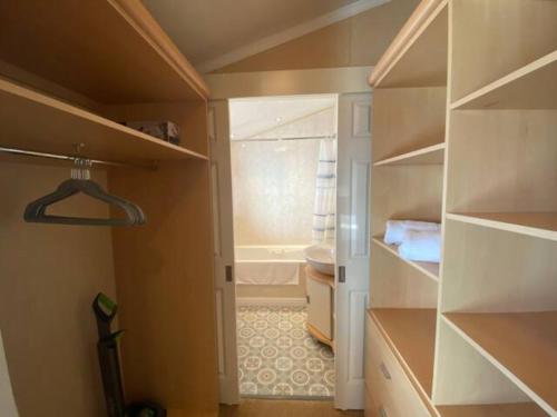 a bathroom with a walk in closet with a toilet at Hot Tub Lodge with Panoramic Views & Free Golf in Swarland