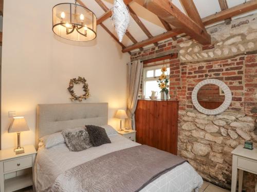 a bedroom with a bed and a brick wall at Fulmar Cottage in Bridlington