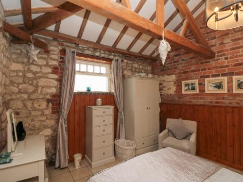 a bedroom with a bed and a brick wall at Fulmar Cottage in Bridlington