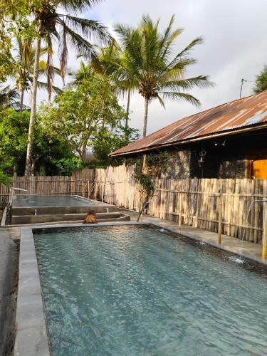 a swimming pool in front of a house with palm trees at Volcano Bali House in Kubupenlokan