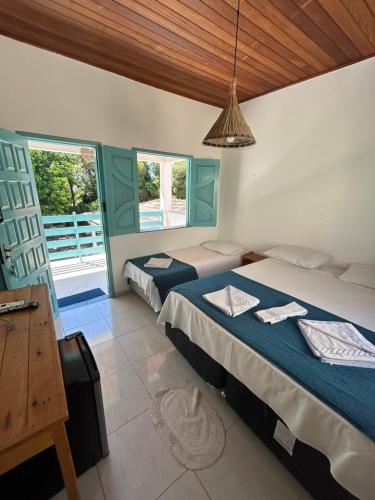 um quarto com 2 camas, uma mesa e janelas em Jambo 1 em Marau