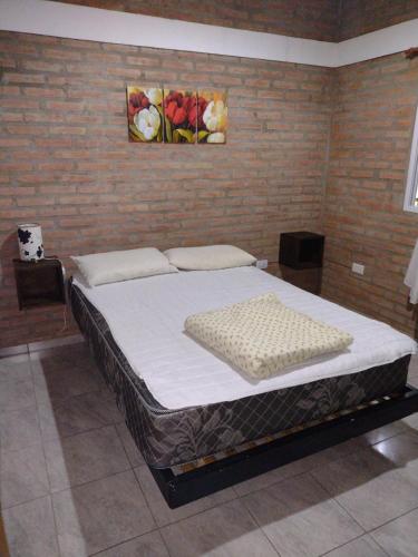 Cama grande en habitación con pared de ladrillo en Cabañas La Peperina 2 in 