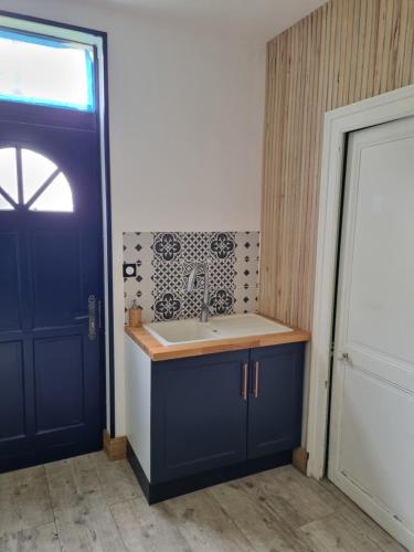 uma cozinha com um lavatório e uma porta azul em Gîte Les Plantis - Cognac em Cherves-de-Cognac