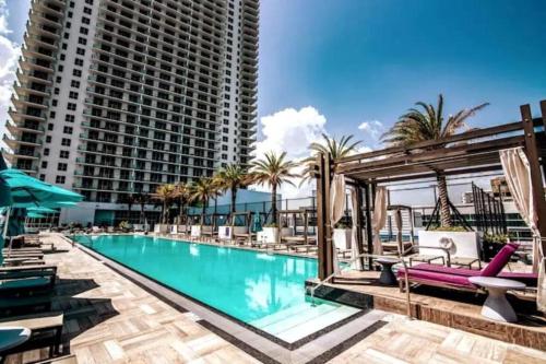 a swimming pool with chaise lounge chairs and a large building at Miami Sunset City View 1809 in Miami