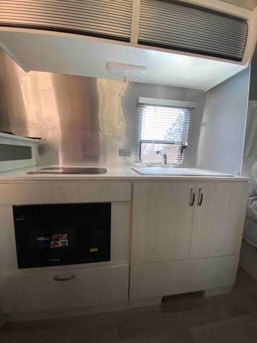 a kitchen with a stove top oven next to a sink at Modern Airstream with amazing view - 10 to 15 minutes from Kings Canyon National Park in Dunlap