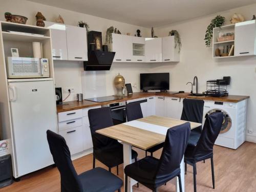 une cuisine avec des armoires blanches et une table et des chaises en bois dans l'établissement Maison au bord de Marne, à Maisons-Alfort