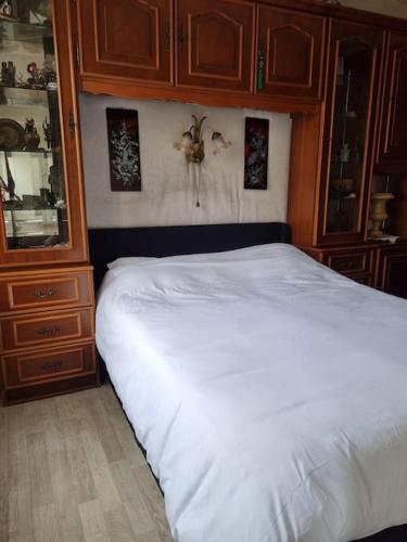 - une chambre avec un lit blanc et des placards en bois dans l'établissement Maison au bord de Marne, à Maisons-Alfort