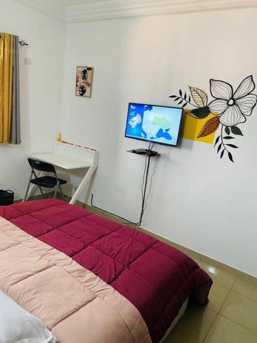 1 dormitorio con 1 cama y TV en la pared en 2 pièces très moderne à Cocody Angré Château, en Cocody