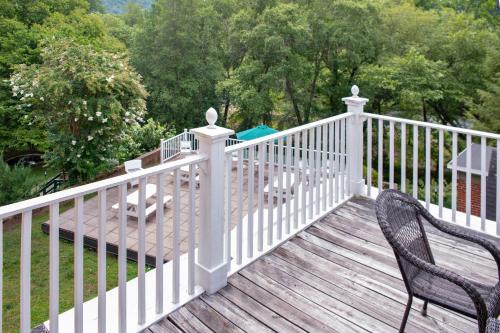 a white fence on a wooden deck with two chairs at Elk River Hotel & Cafe in Sutton