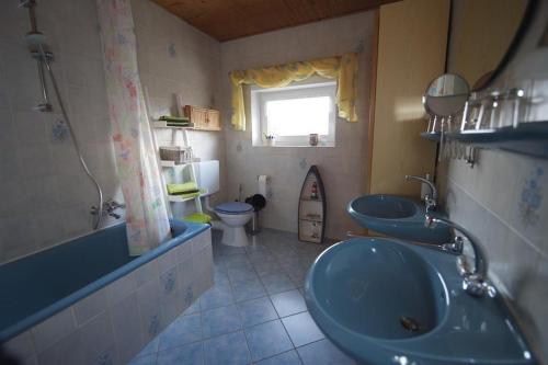 a bathroom with two sinks and a toilet and a window at Ferienwohnung Kribs in Arzfeld