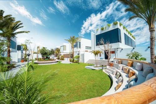 - une vue sur l'extérieur d'une maison avec une pelouse et des palmiers dans l'établissement Nas House Private Villas, à Dubaï
