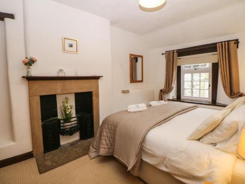 a bedroom with a bed and a fireplace at Harrow Cottage in Bakewell