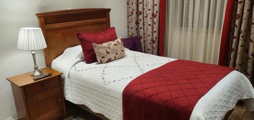 a bedroom with a red and white bed with a lamp at Hotel Puerta del Lago in Puerto Varas