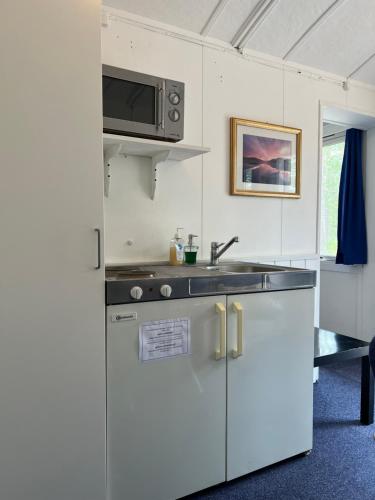 eine Küche mit einer Spüle und einer Mikrowelle in der Unterkunft Rena HOSTEL EINARA in Rena