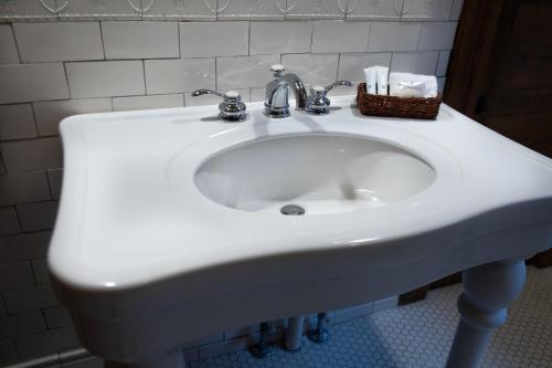 a white sink in a bathroom with a basket on it at Elk River Hotel & Cafe in Sutton