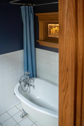 a bath tub in a bathroom with a blue shower curtain at Elk River Hotel & Cafe in Sutton