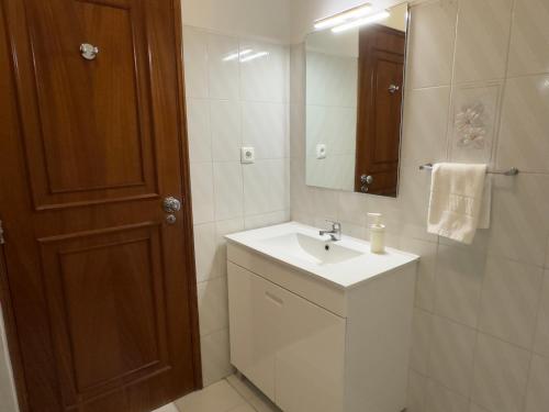 een witte badkamer met een wastafel en een spiegel bij Apartamento Margarita in Quarteira