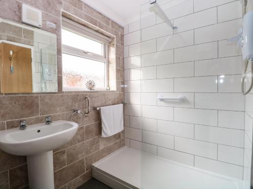 a white bathroom with a sink and a mirror at 21 Siesta Mar in Mundesley