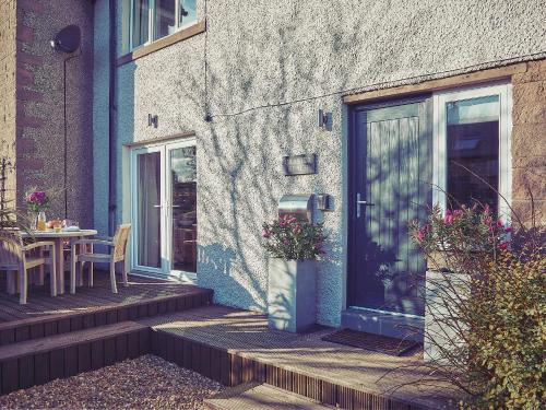 a patio with a table and a door with flowers at Craster Reach in Alnwick