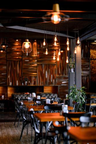 a restaurant with wooden tables and chairs and lights at Gudauri Loft Hotel in Gudauri