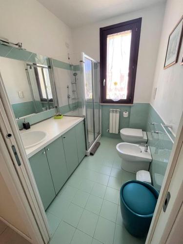 ein Badezimmer mit 2 WCs, einem Waschbecken und einem Spiegel in der Unterkunft TRILO COPPO CON SPIAGGIA E POSTO AUTO in Numana
