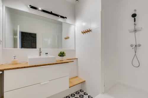 une salle de bain blanche avec un lavabo et un miroir dans l'établissement Bleu Klein - climatisation, wifi, calme, à Toulouse