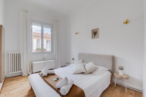 une chambre blanche avec un grand lit et une fenêtre dans l'établissement Bleu Klein - climatisation, wifi, calme, à Toulouse