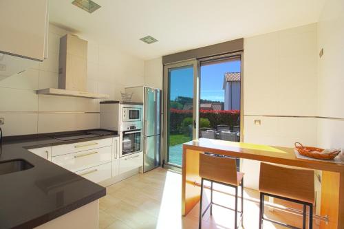 a kitchen with white appliances and a counter with chairs at El Chalet de Lola in Santillana del Mar